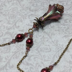 Crimson red and bronze gothic necklace. This handmade vintage style bronze necklace has a central flower drop that has been hand painted in colour shifting red and gold. Vibrant red glass pearls and burgundy crystals are added along the bronze tone chain. Whimsigoth jewelry, Fairytale fantasy necklace.