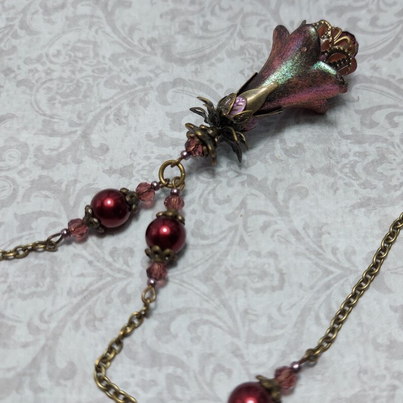 Crimson red and bronze gothic necklace. This handmade vintage style bronze necklace has a central flower drop that has been hand painted in colour shifting red and gold. Vibrant red glass pearls and burgundy crystals are added along the bronze tone chain. Whimsigoth jewelry, Fairytale fantasy necklace.