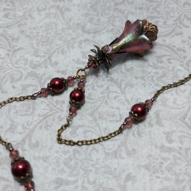Crimson red and bronze gothic necklace. This handmade vintage style bronze necklace has a central flower drop that has been hand painted in colour shifting red and gold. Vibrant red glass pearls and burgundy crystals are added along the bronze tone chain. Whimsigoth jewelry, Fairytale fantasy necklace.