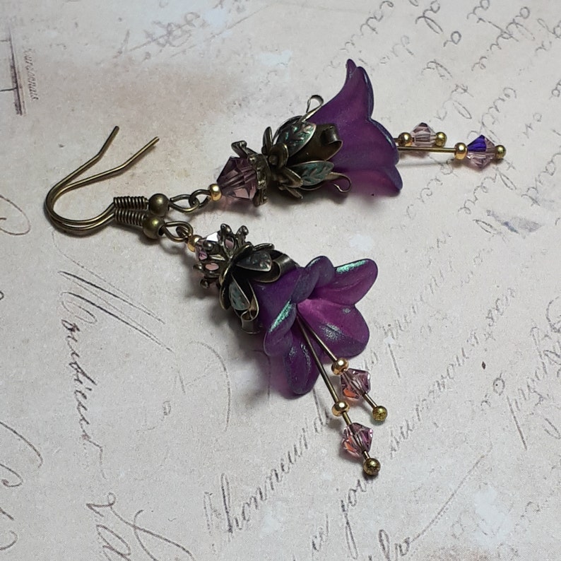 Mulberry purple bell flowers that have been hand painted with an iridescent green shimmer. They have antique bronze floral accents and light amethyst AB crystal drops from the bottoms of the flowers. They are fantasy vintage art nouveau in style.