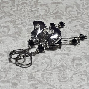 Gothic black vintage fairy flower earrings, delicate fluted flowers have been been paired with antique silver filigree floral bead caps. Jet black crystals are added to crystal drops that sway as the earrings move. Finished with lever back hooks.