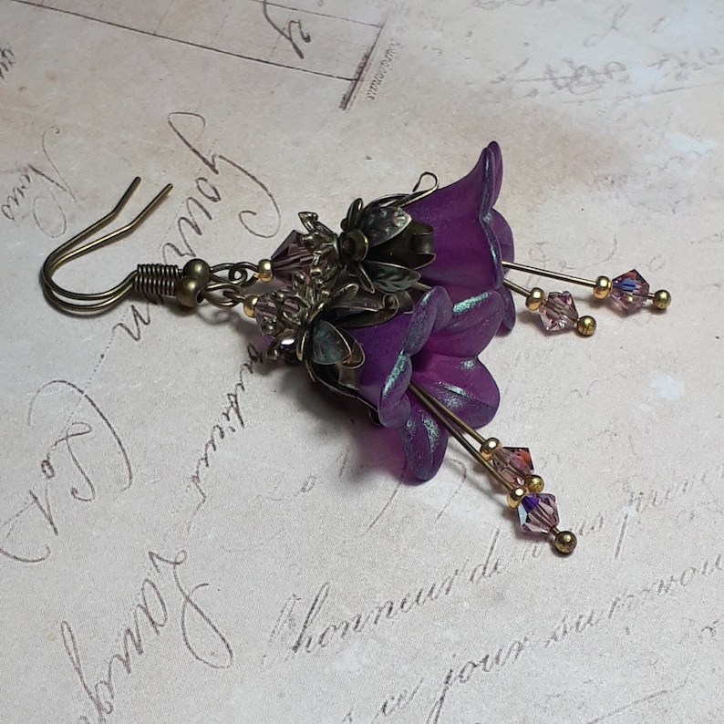 Mulberry purple bell flowers that have been hand painted with an iridescent green shimmer. They have antique bronze floral accents and light amethyst AB crystal drops from the bottoms of the flowers. They are fantasy vintage art nouveau in style.