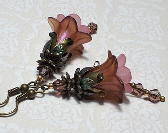 May include: A pair of pink flower-shaped earrings with bronze-colored metal accents and crystal beads.