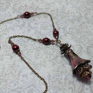 Crimson red and bronze gothic necklace. This handmade vintage style bronze necklace has a central flower drop that has been hand painted in colour shifting red and gold. Vibrant red glass pearls and burgundy crystals are added along the bronze tone chain. Whimsigoth jewelry, Fairytale fantasy necklace.