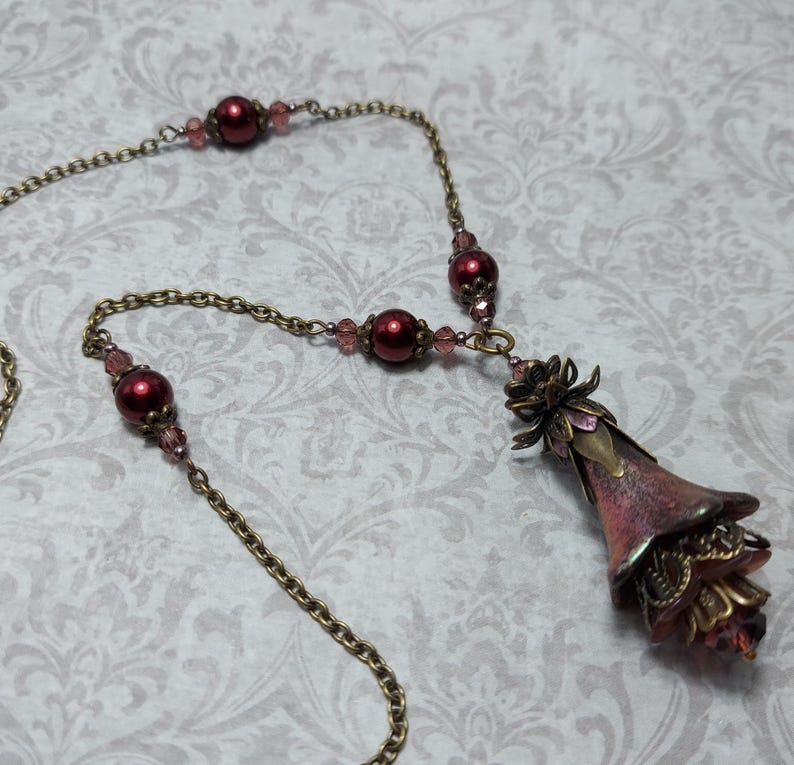 Crimson red and bronze gothic necklace. This handmade vintage style bronze necklace has a central flower drop that has been hand painted in colour shifting red and gold. Vibrant red glass pearls and burgundy crystals are added along the bronze tone chain. Whimsigoth jewelry, Fairytale fantasy necklace.