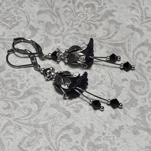 Gothic black vintage fairy flower earrings, delicate fluted flowers have been been paired with antique silver filigree floral bead caps. Jet black crystals are added to crystal drops that sway as the earrings move. Finished with lever back hooks.