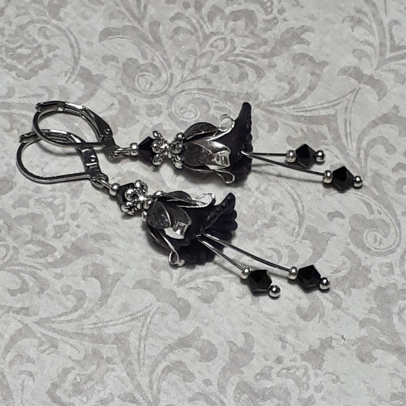 Gothic black vintage fairy flower earrings, delicate fluted flowers have been been paired with antique silver filigree floral bead caps. Jet black crystals are added to crystal drops that sway as the earrings move. Finished with lever back hooks.