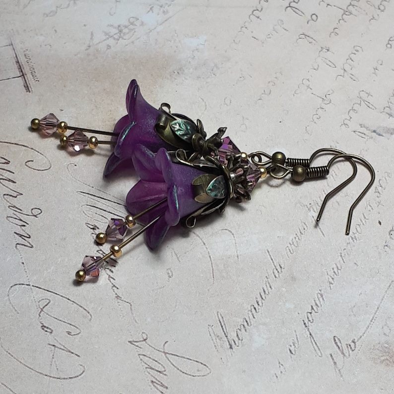 Mulberry purple bell flowers that have been hand painted with an iridescent green shimmer. They have antique bronze floral accents and light amethyst AB crystal drops from the bottoms of the flowers. They are fantasy vintage art nouveau in style.