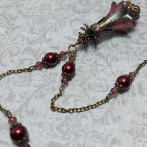 Crimson red and bronze gothic necklace. This handmade vintage style bronze necklace has a central flower drop that has been hand painted in colour shifting red and gold. Vibrant red glass pearls and burgundy crystals are added along the bronze tone chain. Whimsigoth jewelry, Fairytale fantasy necklace.