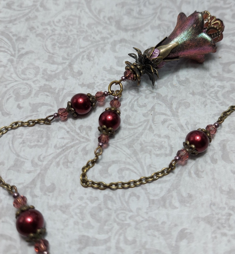 Crimson red and bronze gothic necklace. This handmade vintage style bronze necklace has a central flower drop that has been hand painted in colour shifting red and gold. Vibrant red glass pearls and burgundy crystals are added along the bronze tone chain. Whimsigoth jewelry, Fairytale fantasy necklace.