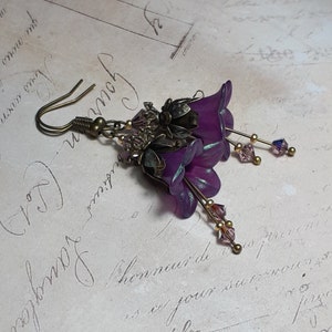 Mulberry purple bell flowers that have been hand painted with an iridescent green shimmer. They have antique bronze floral accents and light amethyst AB crystal drops from the bottoms of the flowers. They are fantasy vintage art nouveau in style.