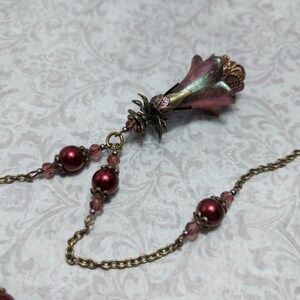 Crimson red and bronze gothic necklace. This handmade vintage style bronze necklace has a central flower drop that has been hand painted in colour shifting red and gold. Vibrant red glass pearls and burgundy crystals are added along the bronze tone chain. Whimsigoth jewelry, Fairytale fantasy necklace.