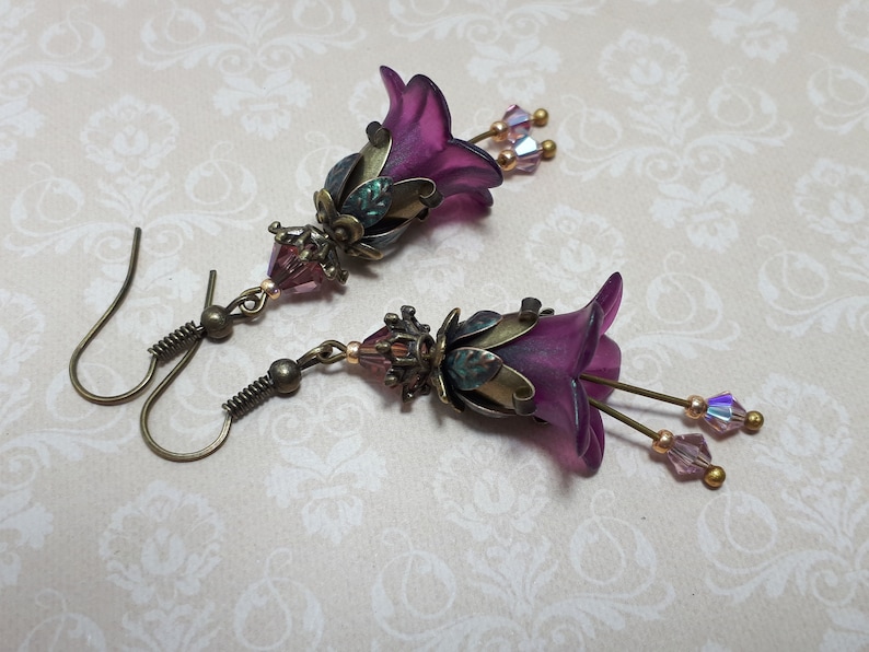 Mulberry purple bell flowers that have been hand painted with an iridescent green shimmer. They have antique bronze floral accents and light amethyst AB crystal drops from the bottoms of the flowers. They are fantasy vintage art nouveau in style.