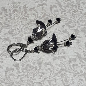 Gothic black vintage fairy flower earrings, delicate fluted flowers have been been paired with antique silver filigree floral bead caps. Jet black crystals are added to crystal drops that sway as the earrings move. Finished with lever back hooks.