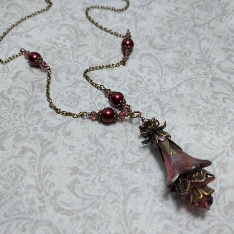 Crimson red and bronze gothic necklace. This handmade vintage style bronze necklace has a central flower drop that has been hand painted in colour shifting red and gold. Vibrant red glass pearls and burgundy crystals are added along the bronze tone chain. Whimsigoth jewelry, Fairytale fantasy necklace.