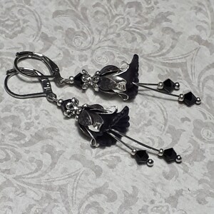 Gothic black vintage fairy flower earrings, delicate fluted flowers have been been paired with antique silver filigree floral bead caps. Jet black crystals are added to crystal drops that sway as the earrings move. Finished with lever back hooks.
