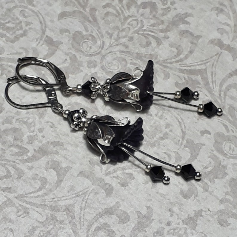 Gothic black vintage fairy flower earrings, delicate fluted flowers have been been paired with antique silver filigree floral bead caps. Jet black crystals are added to crystal drops that sway as the earrings move. Finished with lever back hooks.