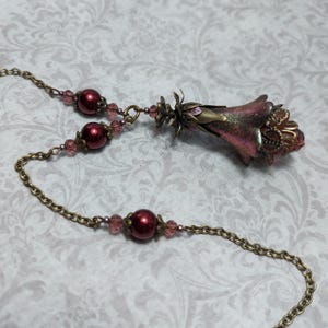 Crimson red and bronze gothic necklace. This handmade vintage style bronze necklace has a central flower drop that has been hand painted in colour shifting red and gold. Vibrant red glass pearls and burgundy crystals are added along the bronze tone chain. Whimsigoth jewelry, Fairytale fantasy necklace.