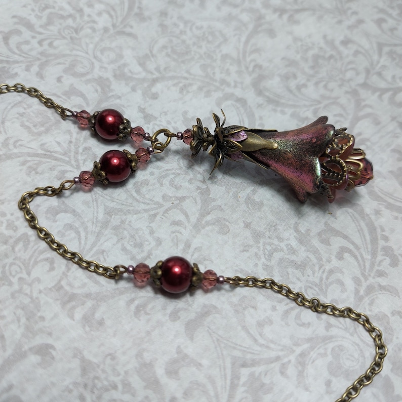 Crimson red and bronze gothic necklace. This handmade vintage style bronze necklace has a central flower drop that has been hand painted in colour shifting red and gold. Vibrant red glass pearls and burgundy crystals are added along the bronze tone chain. Whimsigoth jewelry, Fairytale fantasy necklace.