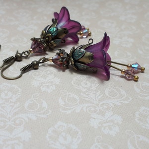 Mulberry purple bell flowers that have been hand painted with an iridescent green shimmer. They have antique bronze floral accents and light amethyst AB crystal drops from the bottoms of the flowers. They are fantasy vintage art nouveau in style.