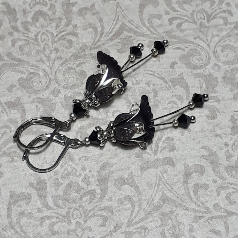 Gothic black vintage fairy flower earrings, delicate fluted flowers have been been paired with antique silver filigree floral bead caps. Jet black crystals are added to crystal drops that sway as the earrings move. Finished with lever back hooks.