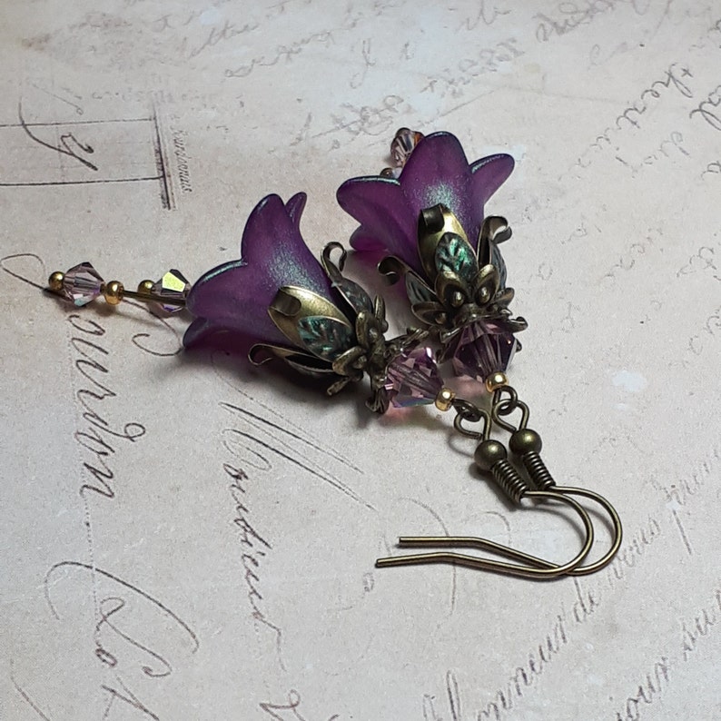 Mulberry purple bell flowers that have been hand painted with an iridescent green shimmer. They have antique bronze floral accents and light amethyst AB crystal drops from the bottoms of the flowers. They are fantasy vintage art nouveau in style.