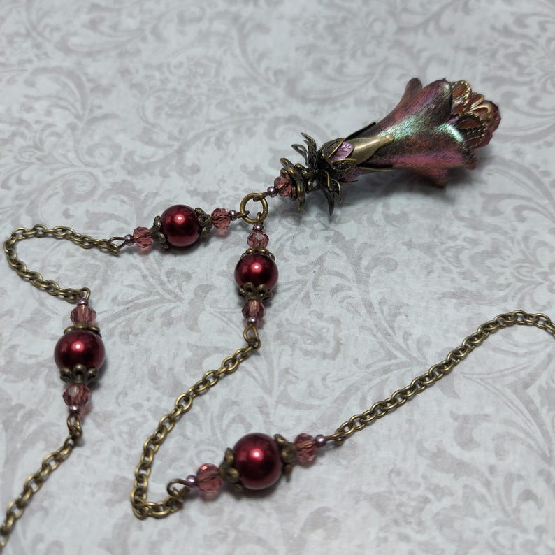 Crimson red and bronze gothic necklace. This handmade vintage style bronze necklace has a central flower drop that has been hand painted in colour shifting red and gold. Vibrant red glass pearls and burgundy crystals are added along the bronze tone chain. Whimsigoth jewelry, Fairytale fantasy necklace.