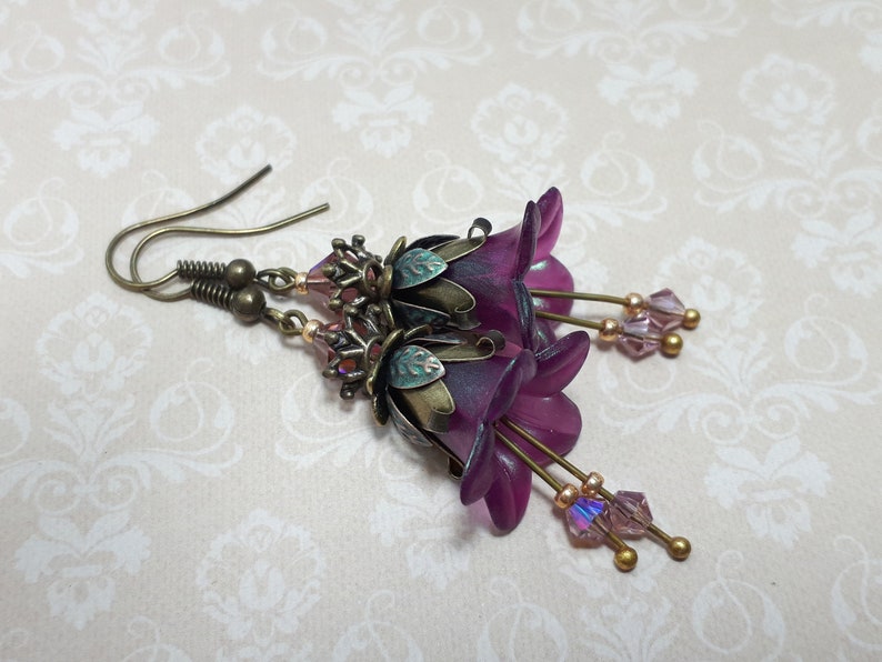 Mulberry purple bell flowers that have been hand painted with an iridescent green shimmer. They have antique bronze floral accents and light amethyst AB crystal drops from the bottoms of the flowers. They are fantasy vintage art nouveau in style.