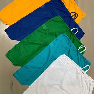 May include: Five drawstring mesh bags in different colours: yellow, blue, green, teal, and white. The bags are stacked on top of each other, with the yellow bag on top and the white bag at the bottom.