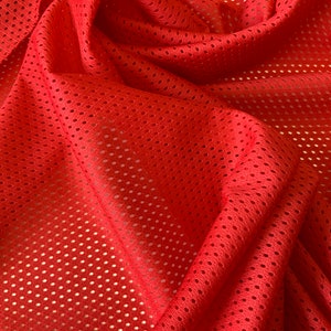 Peut inclure: Tissu en maille rouge avec un motif texturé et tissé. Le tissu est plié et drapé, montrant la texture et le tissage du matériau.