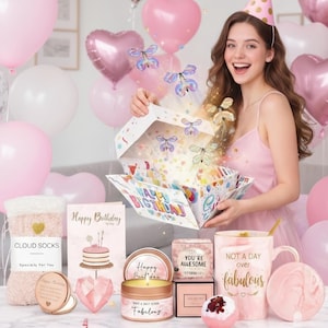 May include: A birthday-themed gift set with pink and white balloons. The set includes a gift box with butterflies, a mug, a candle, a bath bomb, a compact mirror, a greeting card, and fuzzy socks labeled "Cloud Socks."