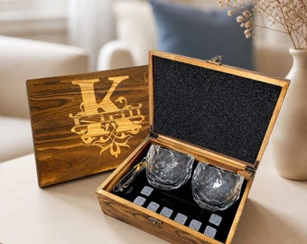 May include: A dark stained wooden gift box with a hinged lid featuring a laser-engraved letter K and the name Kirill. Inside, the box contains two faceted crystal whiskey glasses and a set of eight grey stone whiskey chilling cubes.