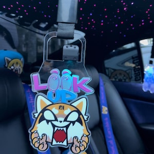 May include: A clear plastic car charm with a red and white cartoon character with the words "Look Up" in pink and blue letters.