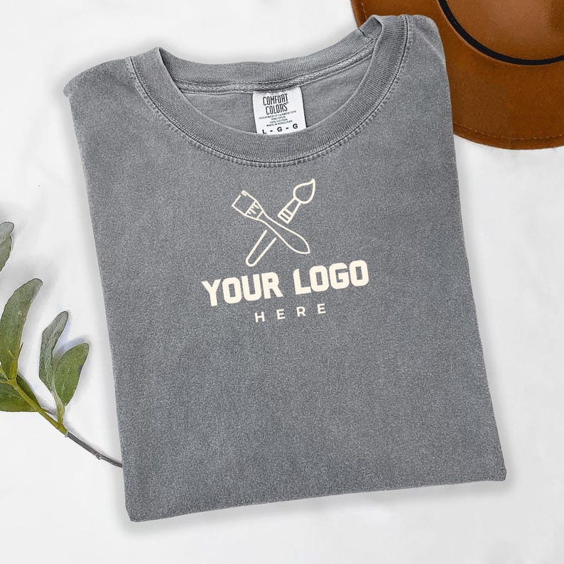 May include: Gray t-shirt with a white paintbrush and palette logo and the text "YOUR LOGO HERE".