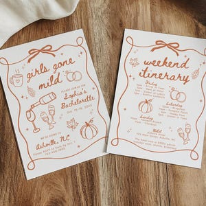 May include: Two white rectangular cards with rust-colored line art and text. The left card reads girls gone mild, Sophia's Bachelorette, Asheville, NC. The right card reads weekend itinerary with a schedule for Friday, Saturday, Sunday, and Monday.