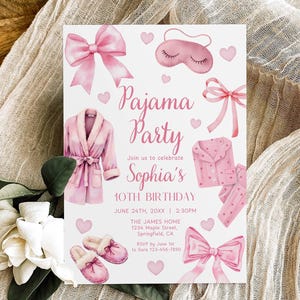 Peut inclure: Une invitation blanche avec des illustrations à l'aquarelle rose pour une soirée pyjama. La carte présente un peignoir rose, un pyjama, des chaussons, des nœuds, des cœurs et le texte "Pajama Party" et "10e anniversaire de Sophia".