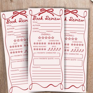 Puede incluir: Tres hojas rosas de reseñas de libros con bordes decorativos y texto en rojo. Cada hoja tiene espacios para el título, el autor, el género y las calificaciones. Una taza de café está sobre un platillo a la derecha.