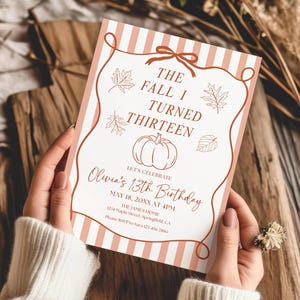 Puede incluir: Una tarjeta de invitación de cumpleaños rectangular con fondo blanco y rayas verticales color melocotón. El texto dice: THE FALL I TURNED THIRTEEN, LET'S CELEBRATE, Olivia's 13th Birthday, MAY 18, 20XX AT 4PM, THE JAMES HOME, 1234 Maple Street, Springfield, CA, Please RSVP to Sara 123 456 7890. El diseño incluye dibujos de líneas marrones de hojas de arce y una calabaza dentro de un borde decorativo con un lazo.