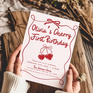Op de afbeelding: Een witte uitnodigingskaart met rode tekst en illustraties. De tekst luidt "Olivia's Cherry First Birthday" en bevat details voor een feest op 14 februari. De illustratie toont twee rode kersen met stelen en bladeren.