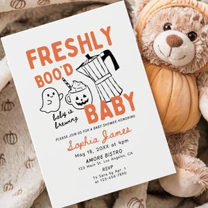 May include: A white rectangular baby shower invitation card featuring orange and black text that reads FRESHLY BOO'D BABY, baby is brewing, and details for Sophia James on May 18, 20XX. The card includes illustrations of a ghost, a jack-o'-lantern mug, and a coffee pot.