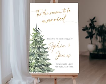 May include: A white wedding welcome sign with a watercolor illustration of a green pine tree with gold lights. The text reads "Tis the season to be married" and "Welcome to the wedding of Sophia & James" with the date "October 27th, 20XX" and location "New York, New York".