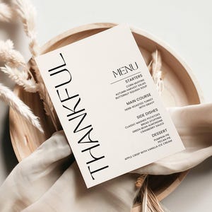 May include: A minimalist Thanksgiving menu card with the word "THANKFUL" printed vertically in black on a cream background. The menu includes starters, main course, side dishes, and dessert.
