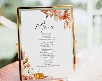 May include: A gold-framed menu with a fall-themed design. The menu lists a Thanksgiving dinner with starters, main course, side dishes, and dessert. The menu includes items like corn muffins, herb-roasted turkey, classic mashed potatoes, pumpkin pie, and pecan pie.
