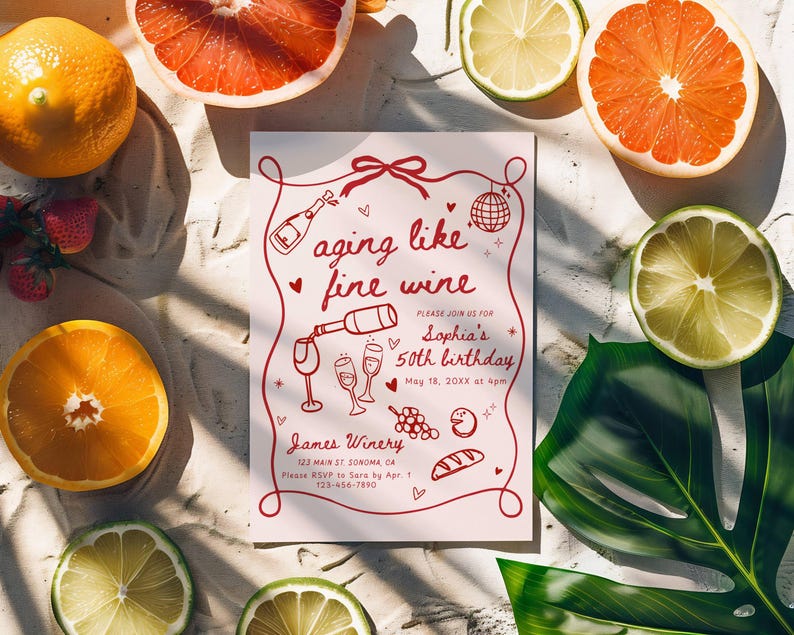 May include: A pink invitation with the text "aging like fine wine" surrounded by illustrations of wine bottles, glasses, and grapes. The invitation is surrounded by sliced citrus fruits, strawberries, and a green leaf.