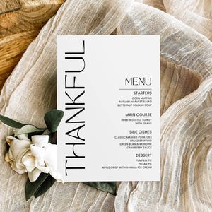 May include: A white card with black text that reads "THANKFUL" on the left side and a Thanksgiving menu on the right side. The menu includes starters, main course, side dishes, and dessert.