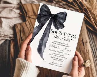 May include: A white rectangular bridal shower invitation card featuring a large black watercolor bow illustration. The text reads: SHE'S TYING the knot, PLEASE JOIN US FOR A BRIDAL SHOWER HONORING Sophia James, SEPTEMBER 23TH, 20XX, 2:30PM, THE JAMES HOME, 1234 Maple Street, Springfield, CA, Please RSVP by August 1st to Sara 123-456 7890, Registered at William Sonoma & Target.