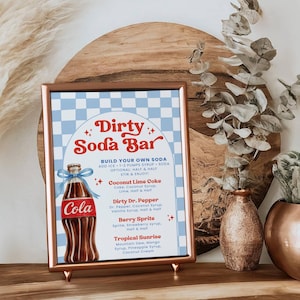 May include: A framed sign with a copper-colored frame that reads "Dirty Soda Bar." The sign features a blue and white checkered background and a graphic of a cola bottle. The sign also lists soda flavor combinations.