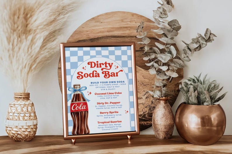 May include: A framed sign with a copper-colored frame that reads "Dirty Soda Bar." The sign features a blue and white checkered background and a graphic of a cola bottle. The sign also lists soda flavor combinations.