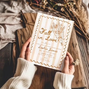 May include: A rectangular bridal shower invitation with a scalloped edge and beige vertical stripes. The card features a brown line-art bouquet of flowers and a pumpkin, with the text Fall in Love, Sophia James, May 18, 20XX at 4pm, AMORE BISTRO, 123 Main St. Los Angeles, CA, RSVP To Sara by Apr. 1 at 123-456-7890.