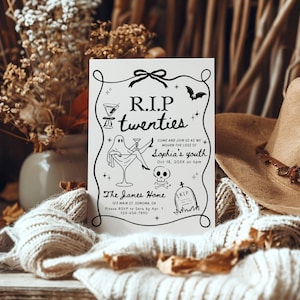 May include: A white invitation card with black text and illustrations for a "R.I.P. twenties" party. The card features a ghost, cocktail glasses, a bat, and a skull. A brown hat and dried flowers are in the background.